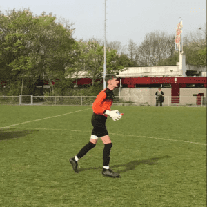 Goalkeeper Luke Stevens wearing orange, playing football