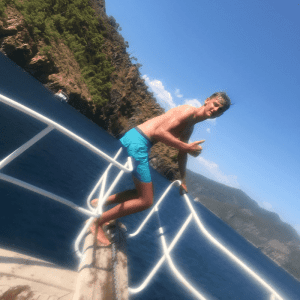 Luke Stevens on holiday, sat beside blue water